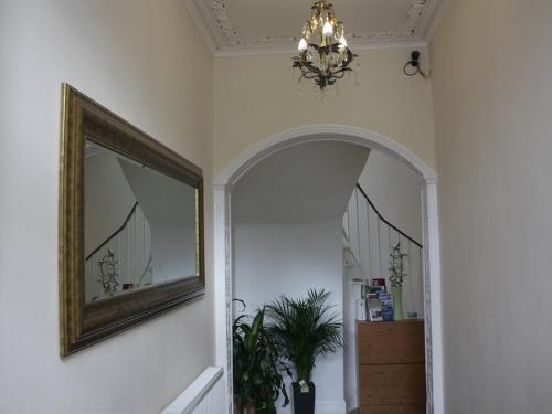 a hallway with a mirror and a chandelier at Edinburgh Holiday Guest House in Edinburgh