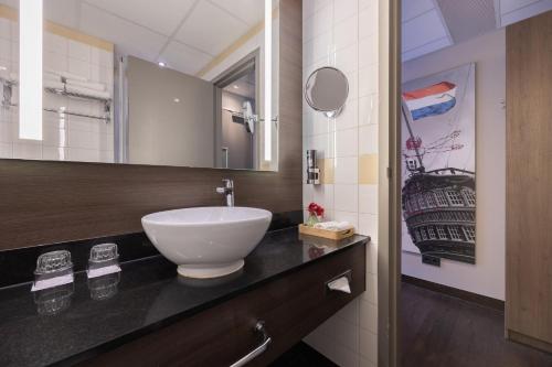een badkamer met een witte wastafel op een aanrecht bij Leonardo Hotel Amsterdam City Center in Amsterdam