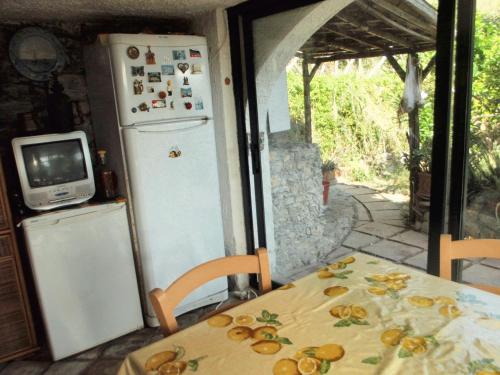 eine Küche mit einem Tisch, einem Kühlschrank und einem TV in der Unterkunft 2 bedrooms house with sea view furnished terrace and wifi at Castelmola 5 km away from the beach in Castelmola