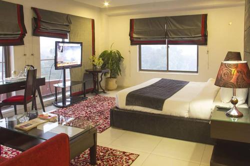 Maisonette Hotels & Resorts في لاهور: غرفة نوم بسرير ومكتب وتلفزيون