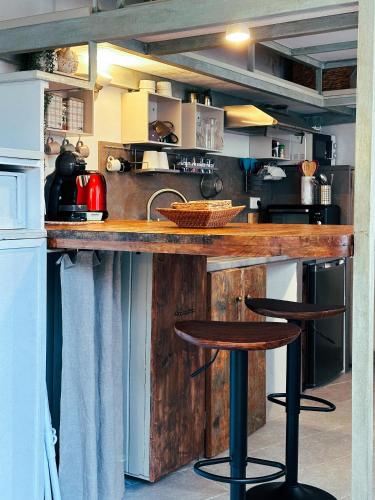 une cuisine avec un comptoir en bois et deux tabourets de bar dans l'établissement Casaluna, centre village, joli petit studio, à Sotta