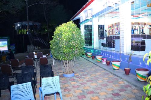 a patio with chairs and a tree in front of a building at Shalini Batika & Eco Resort in Tigri