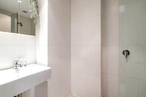 a white bathroom with a sink and a shower at Eclectic Perfectly Positioned Apartment in Sydney