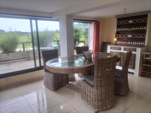 une salle à manger avec une table en verre et des chaises en osier dans l'établissement Ma bohème, à Pouldreuzic