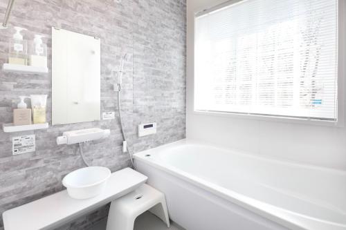 een witte badkamer met een wit bad en een wastafel bij Villa Hanasaku Karuizawa Miyota - Vacation STAY 14347v in Miyota