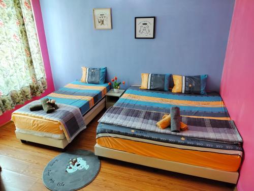 two beds in a room with blue and pink walls at Idea Homestay 1 in Chemor