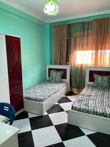 a bedroom with two beds and a checkered floor at Bel appartement meublé à louer in Fort de lʼEau