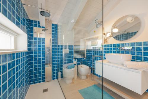a blue tiled bathroom with a sink and a toilet at Jesolo Beach Villa in Lido di Jesolo