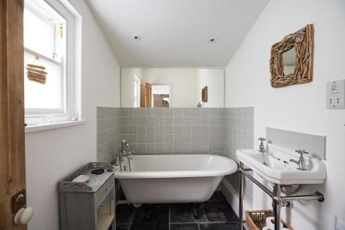 ein weißes Badezimmer mit Badewanne und Waschbecken in der Unterkunft Gull's Nest Holiday Cottage in Mousehole