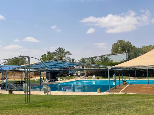 Una gran piscina con un dosel azul alrededor. en ניסים בערבה, en Idan