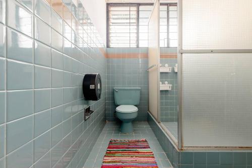 een badkamer met een blauw toilet en een tapijt bij Casa Mundo in San José