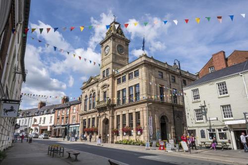 an old building with a clock tower on a street at The Royal Oak Hotel, Welshpool - The Coaching Inn Group in Welshpool
