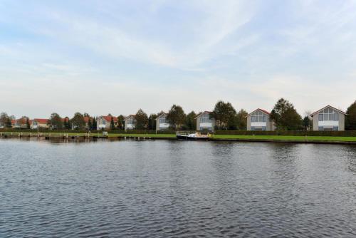 a large body of water with houses and a boat at Summio Villapark Schildmeer in Steendam