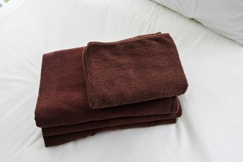 una pila de toallas marrones sentadas en una cama en シティマインド京町802, en Osaka
