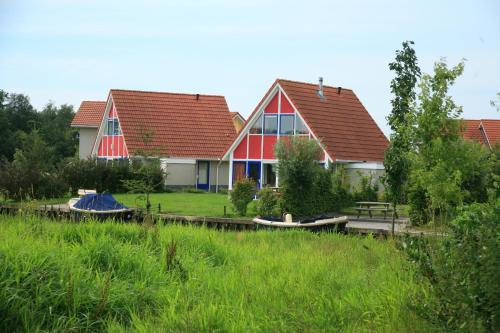 a house with two boats in front of it at Summio Villapark Schildmeer in Steendam