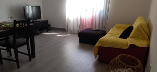 a living room with a table and a chair with a yellow blanket at A Casa da Nocas in Setúbal