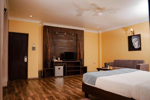 - une chambre avec un lit, un canapé et une télévision dans l'établissement Hotel Maden Inn, à Itahari