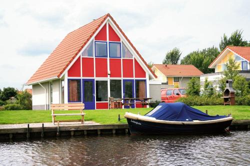 a boat in front of a house on the water at Summio Villapark Schildmeer in Steendam