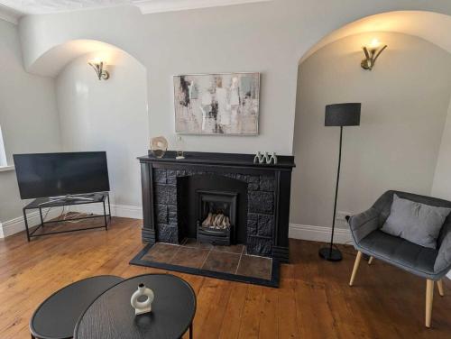ein Wohnzimmer mit einem Kamin und einem TV in der Unterkunft Alexander Apartments Benton Road in Newcastle upon Tyne
