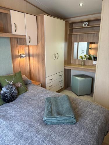 a bedroom with a large bed and a kitchen at Woodpecker lodge, Camelot Holiday Park, CA6 5SZ in Carlisle