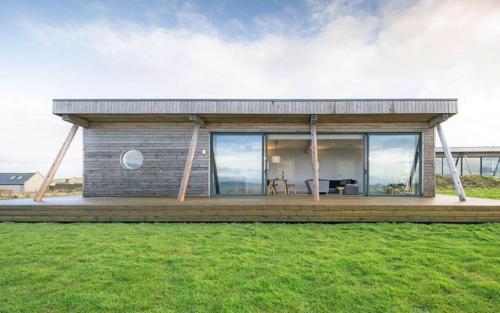 una piccola casa con una terrazza in legno in un campo di Jog Lodge 15 - 3 bed a Wick