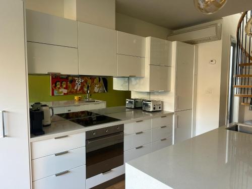 a kitchen with white cabinets and a stove top oven at Stylish 2-Bed Terrace with Private Deck in Melbourne
