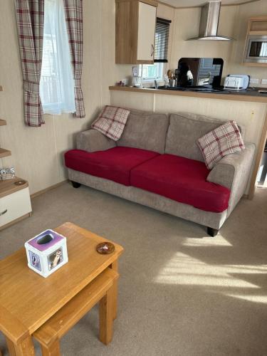 a living room with a red couch and a table at Woodpecker lodge, Camelot Holiday Park, CA6 5SZ in Carlisle