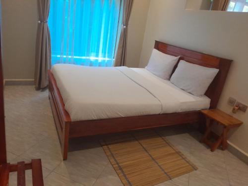 a bedroom with a bed with a wooden frame at BeezBinn in Hoima