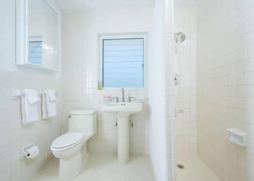 a white bathroom with a toilet and a sink at Beachfront Bliss Private Estate with Cottages in Savannah Sound