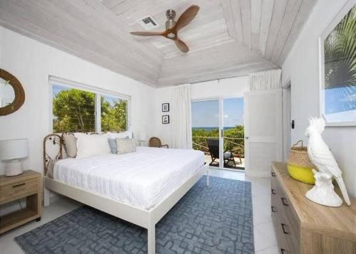 a white bedroom with a bed and a ceiling fan at Beachfront Bliss Private Estate with Cottages in Savannah Sound