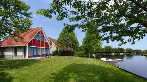 uma casa com um barco na água em Summio Villapark Schildmeer em Steendam