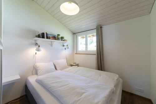a small bedroom with a white bed and a window at Chalet Bergblick in Wildhaus