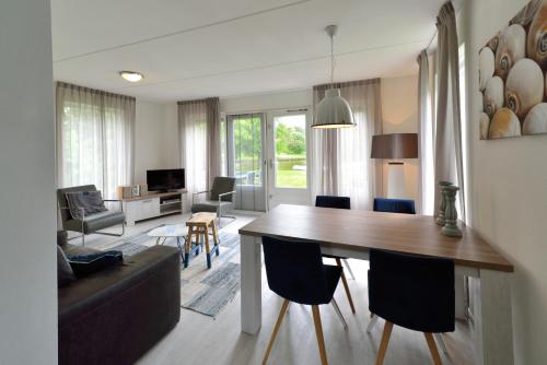 a living room with a dining room table and a couch at Summio Villapark Schildmeer in Steendam