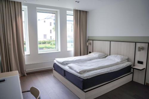 uma cama num quarto com uma grande janela em Comfort Hotel Norrköping em Norrköping