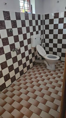 uma casa de banho com um WC em azulejos pretos e brancos em LMR's Budget Stay em Thrissur