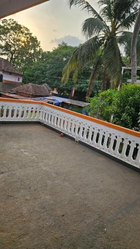 uma cerca branca com uma palmeira ao fundo em LMR's Budget Stay em Thrissur