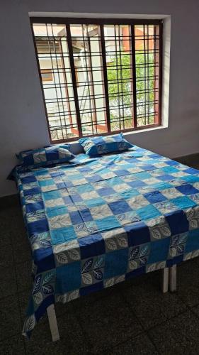 uma cama azul e branca num quarto com uma janela em LMR's Budget Stay em Thrissur