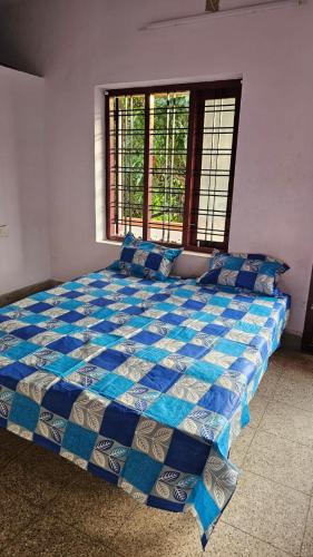 um quarto com uma cama azul e branca e uma janela em LMR's Budget Stay em Thrissur