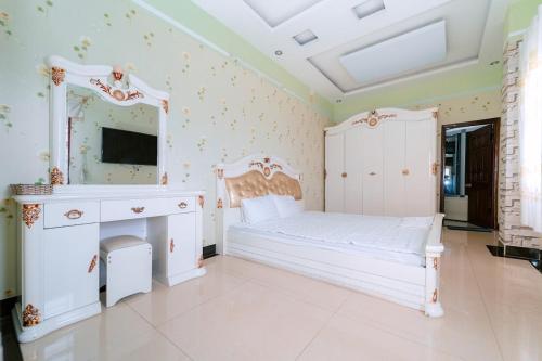 um quarto com uma cama branca, um toucador e um espelho. em FGMN HOTEL Pleiku em Plei Brel (2)