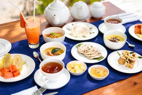 una mesa con platos y tazones de comida y bebida en Club Mango Resort, en Kalpitiya