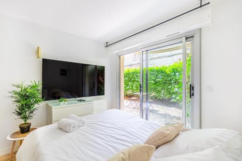 une chambre blanche avec un grand lit et une fenêtre dans l'établissement Lavie Maison Studio avec Jardin, à Bordeaux