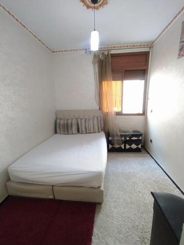 ein Schlafzimmer mit einem weißen Bett und einem Fenster in der Unterkunft Douaa's home in Rabat