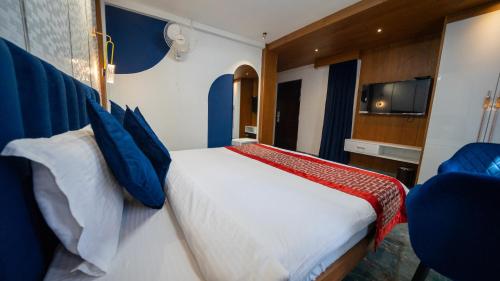 a bedroom with a large white bed with blue pillows at Mystery Maze Resort and Spa in Wayanad