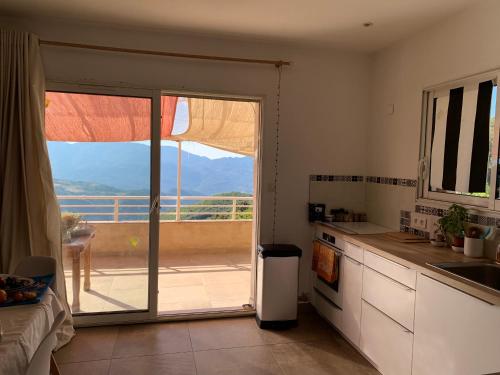 d'une cuisine avec une porte coulissante en verre s'ouvrant sur un balcon. dans l'établissement La Maison de la Fontaine, à Cognocoli-Monticchi