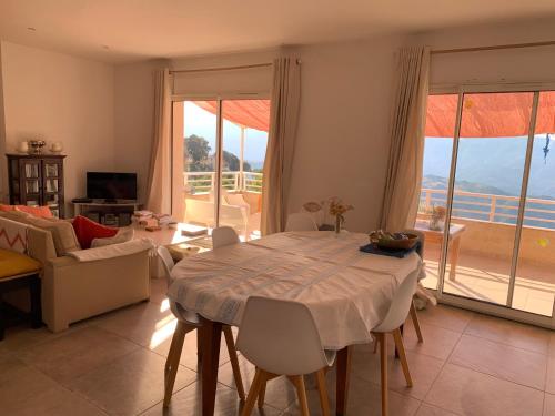- un salon avec une table et une vue sur l'océan dans l'établissement La Maison de la Fontaine, à Cognocoli-Monticchi