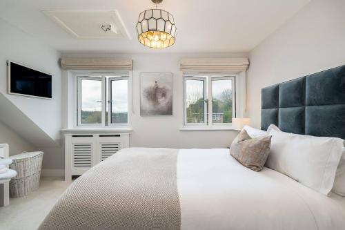 ein weißes Schlafzimmer mit einem großen Bett und Fenstern in der Unterkunft Pass the Keys Bright Modern - Lovely Garden in Chesham