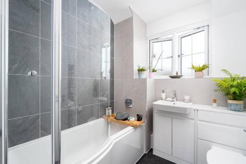 ein Badezimmer mit einer Dusche, einer weißen Badewanne und einem Waschbecken in der Unterkunft Pass the Keys Bright Modern - Lovely Garden in Chesham