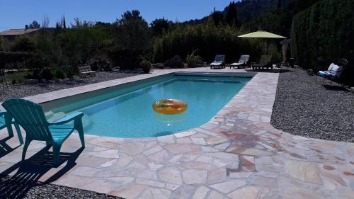 a pool with a chair and a ball in the water at T2 au calme avec piscine in Néoules