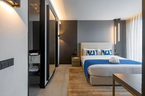 a bedroom with a large bed with blue sheets at Noom Hotel Abidjan Plateau in Abidjan