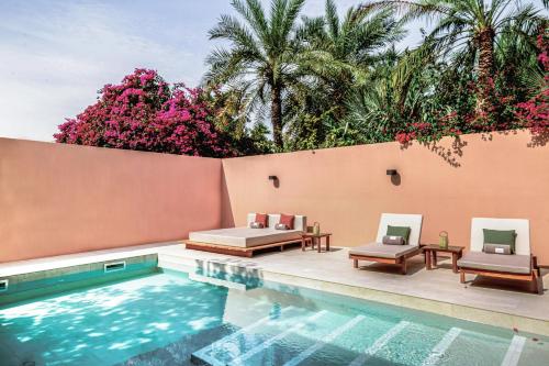 a swimming pool with two lounge chairs next to a wall at Meliá Desert Palm Member of Meliá Collection in Dubai
